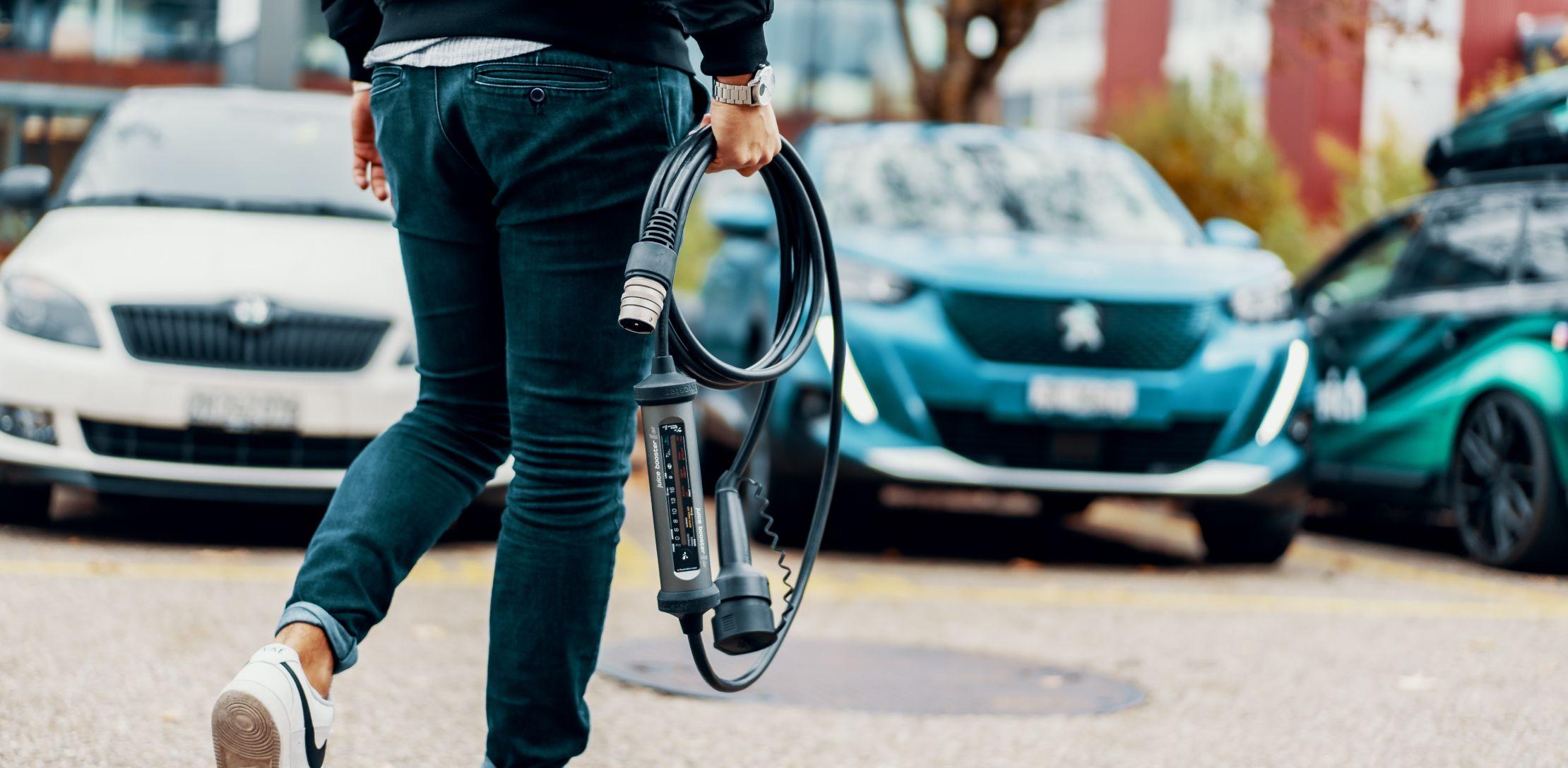 Person trägt mobile Ladestation zum Auto