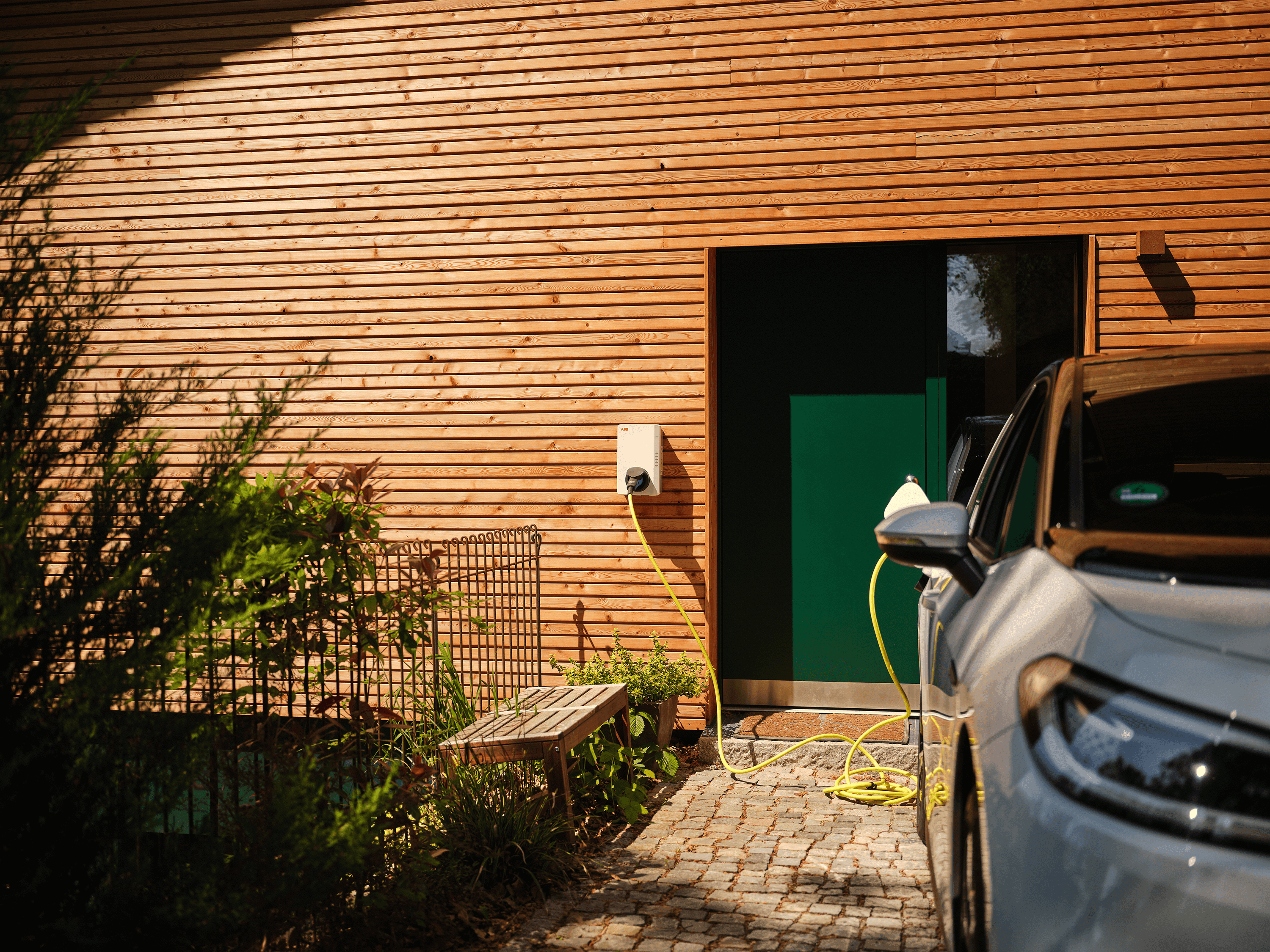 E-Auto lädt an Wallbox vor dem Haus