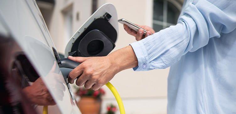 Frau steckt ihr E-Auto an