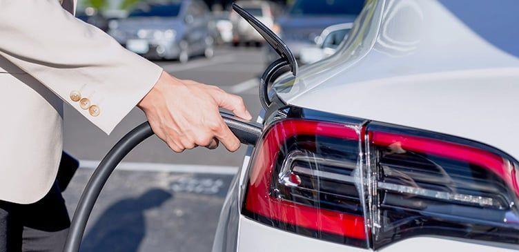 Mann steckt sein E-Auto an