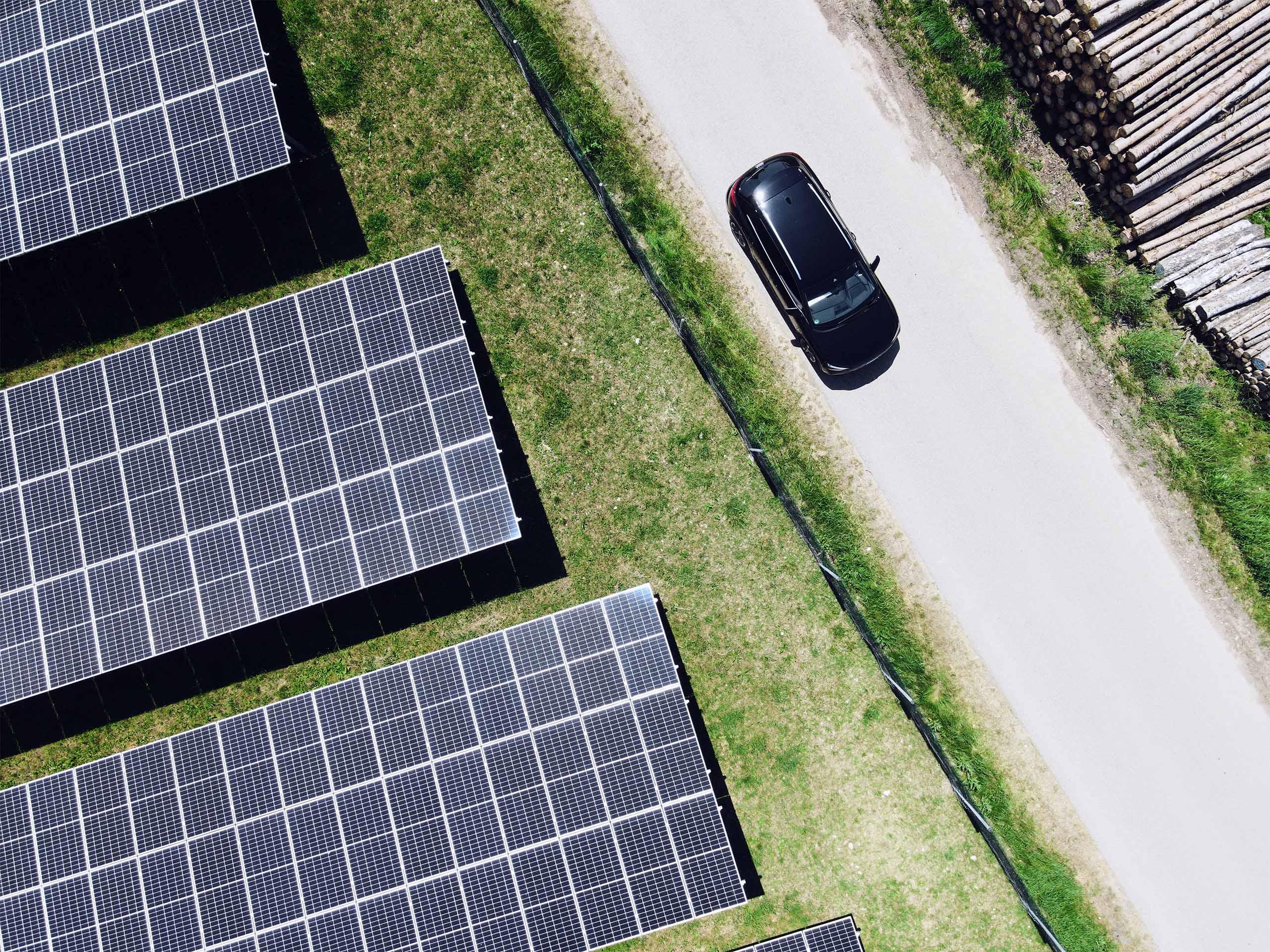 Vogelperspektive: Auto fährt an einem Solarfeld vorbei