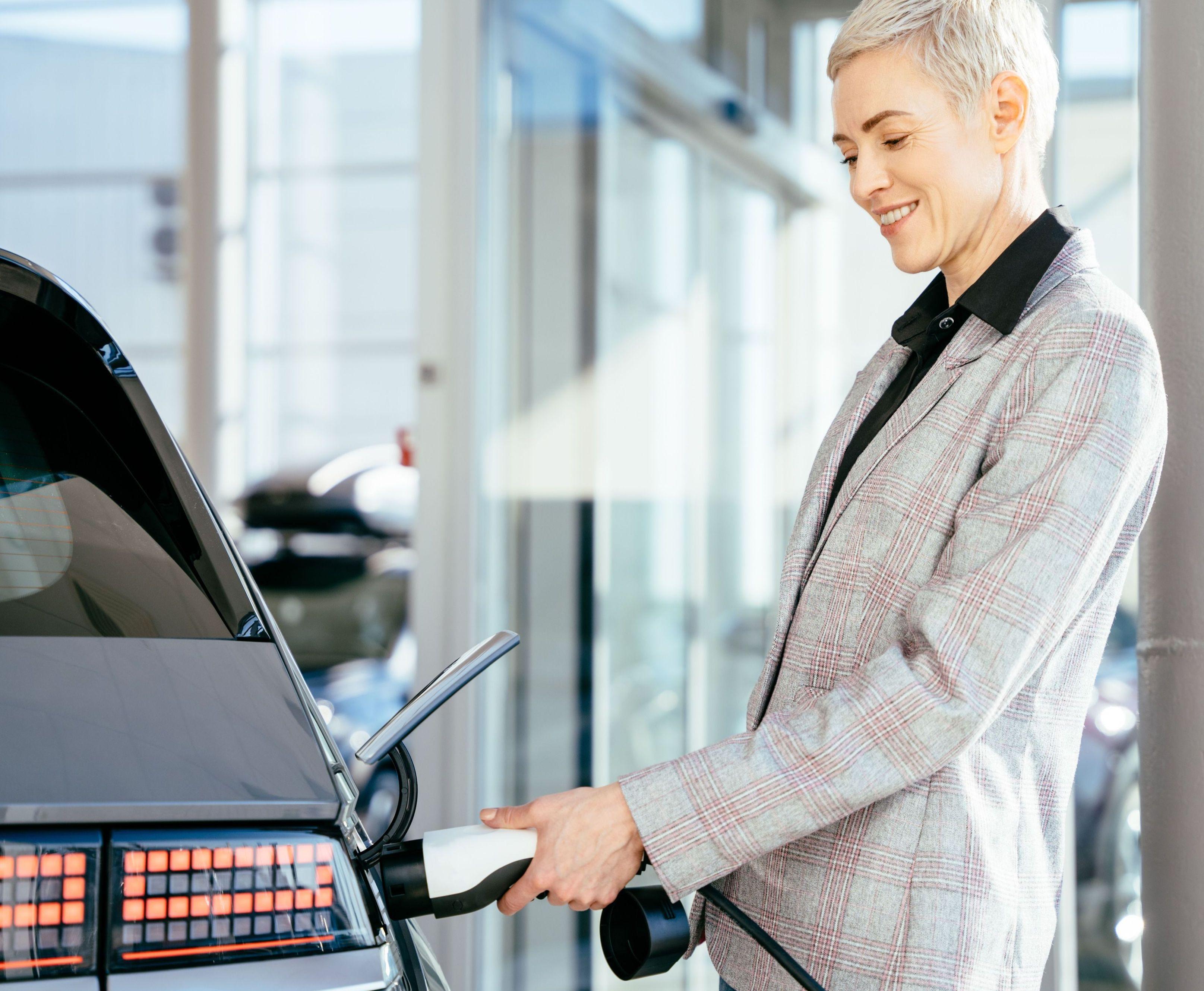 Frau  steckt E-Auto an