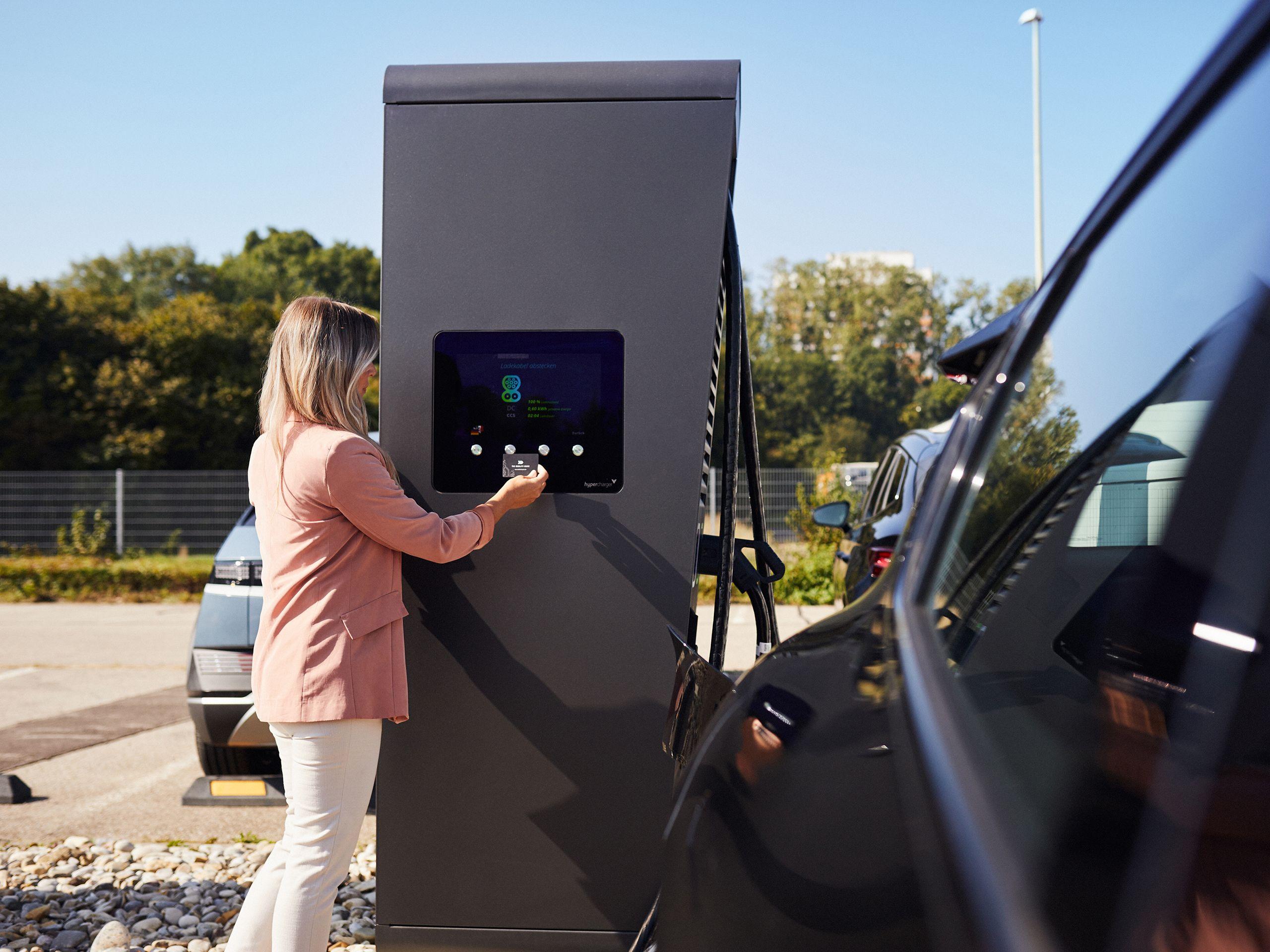 Frau startet Ladevorgang an Schnellladestation mit RFID-Karte