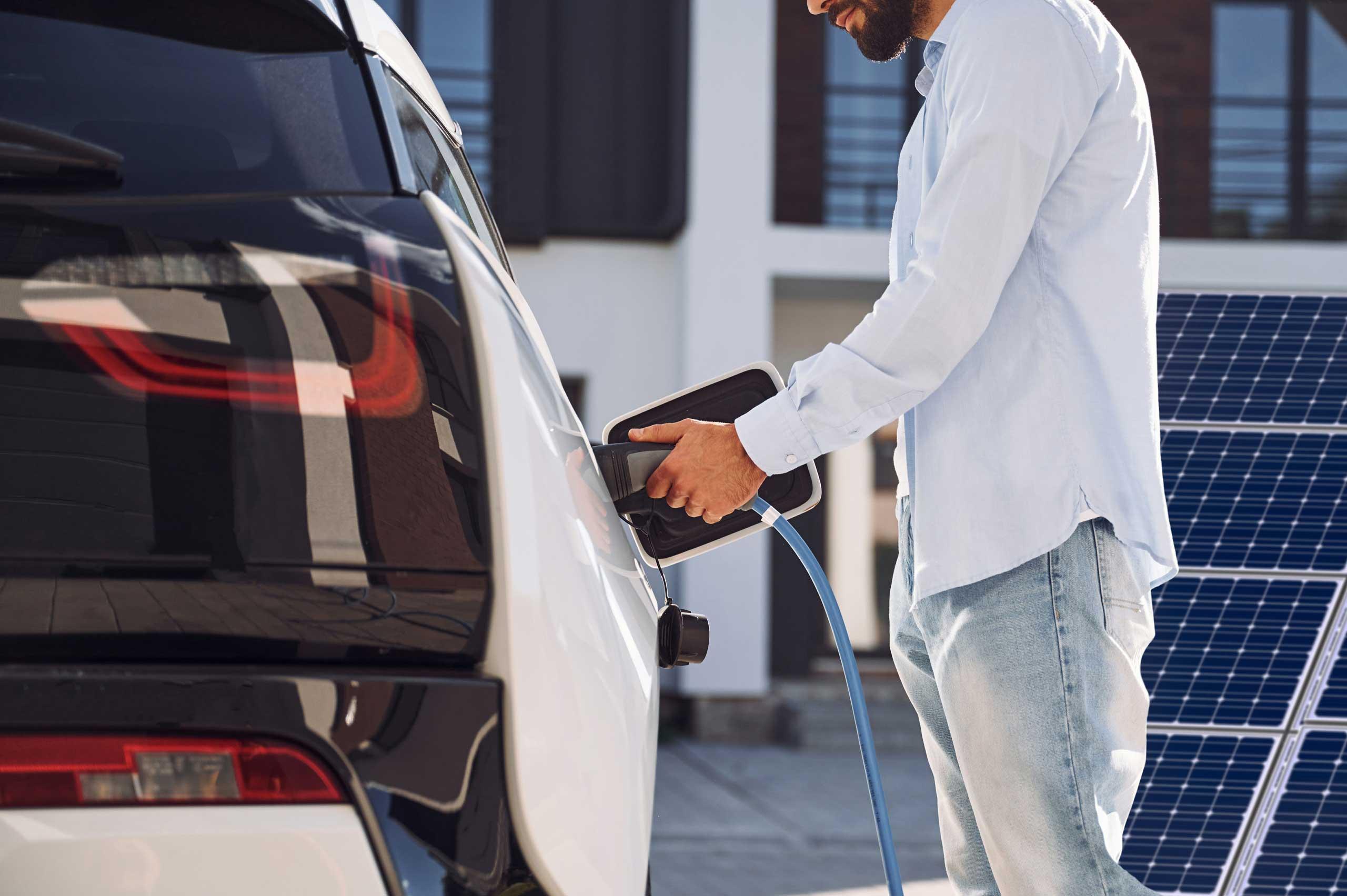 Mann lädt sein E-Auto