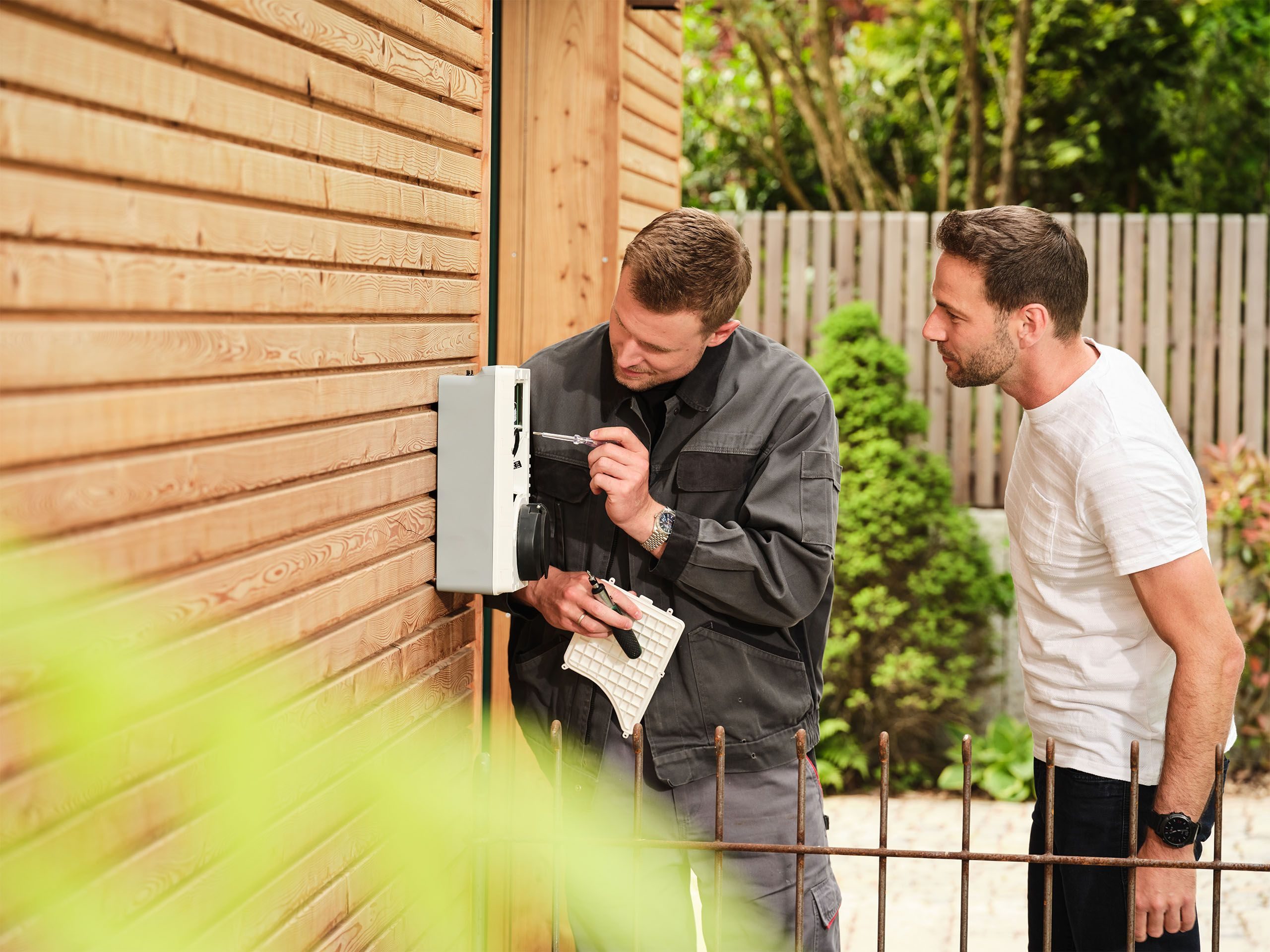 Zwei Maenner blicken auf eine Wallbox