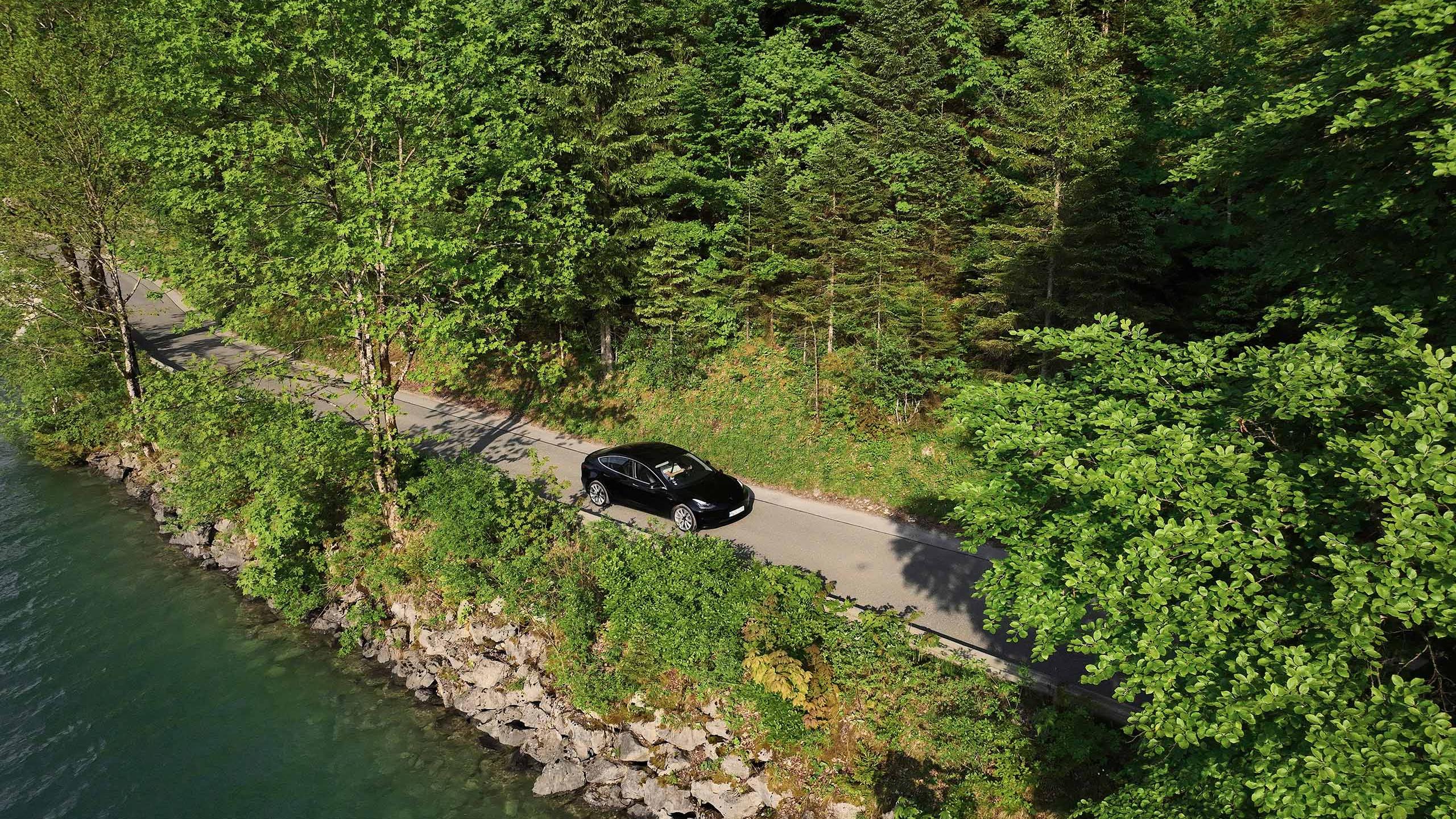 E-Auto faehrt auf einer Straße neben einem See