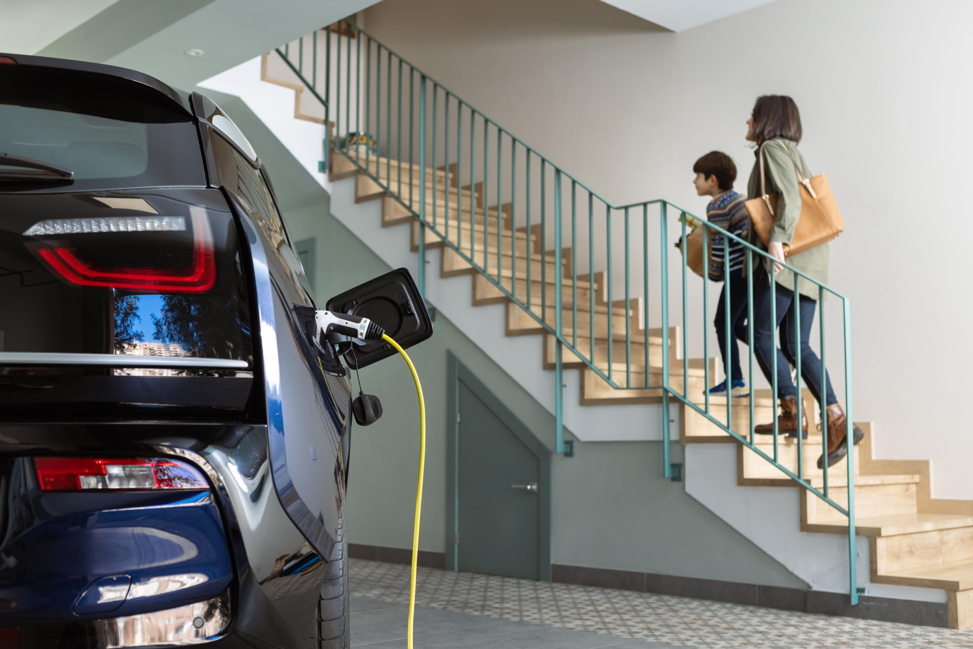 Auto lädt, Mutter und Sohn gehen die Treppe hoch