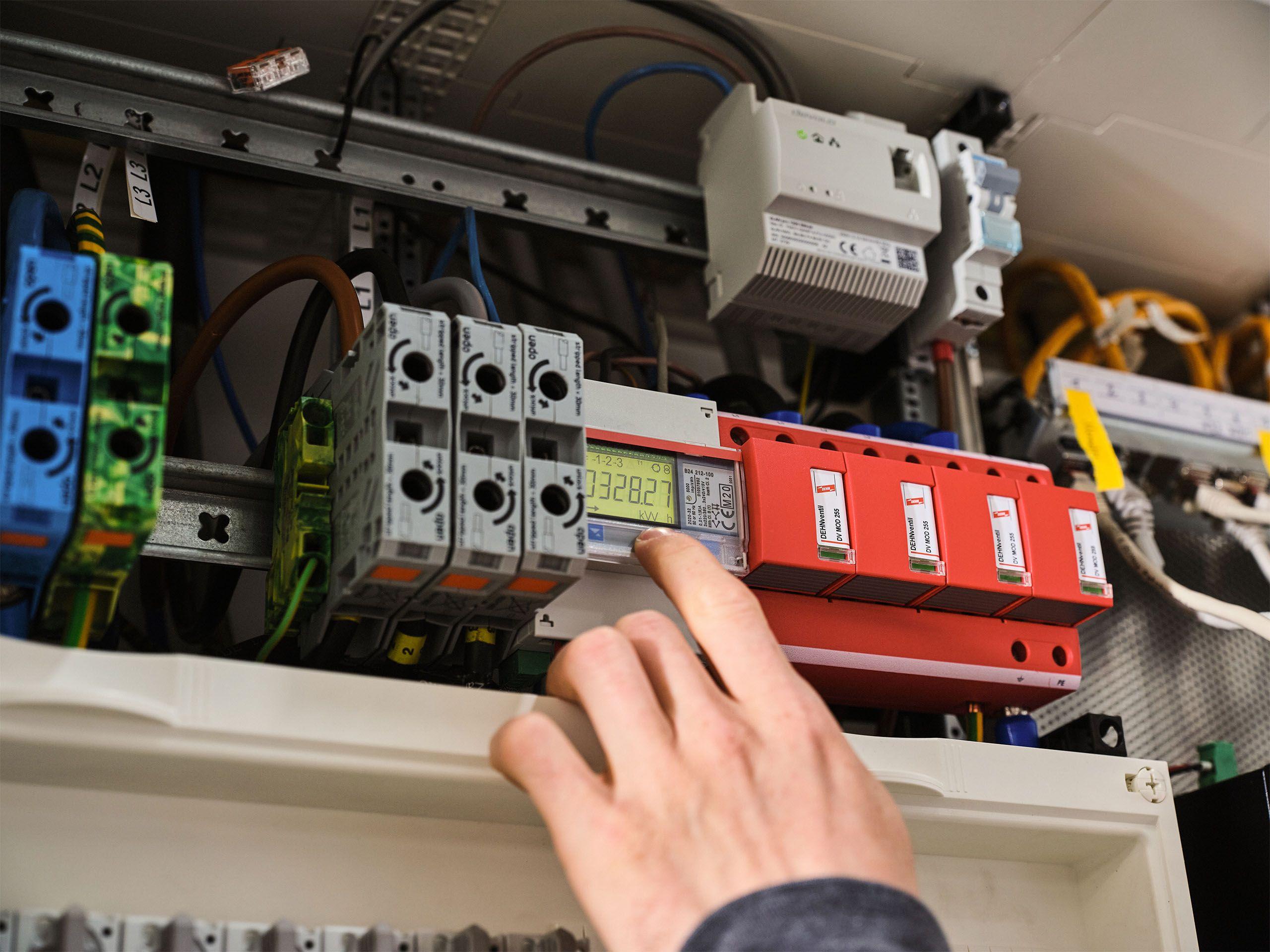 Hand eines Elektrikers am Stromzähler